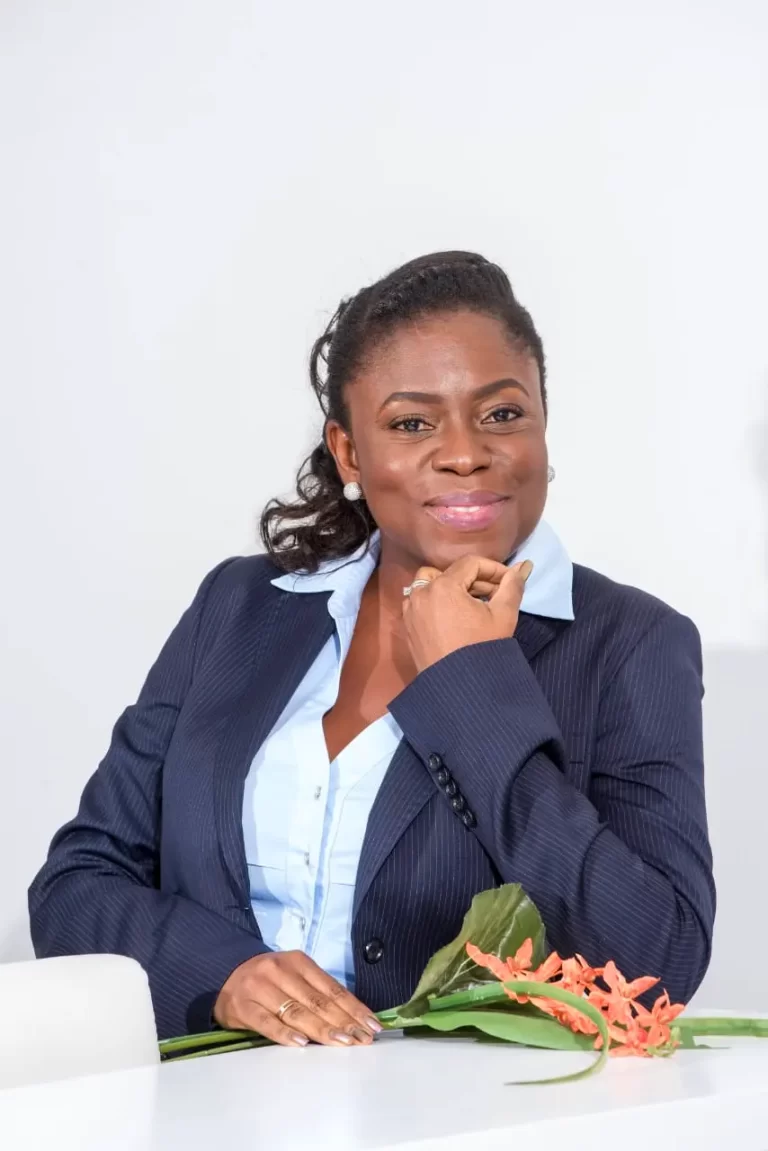 Andreia Soraia Webba David Gaspar Martins, Chairperson of Acumen Global, seated at a desk, smiling confidently in a professional suit.